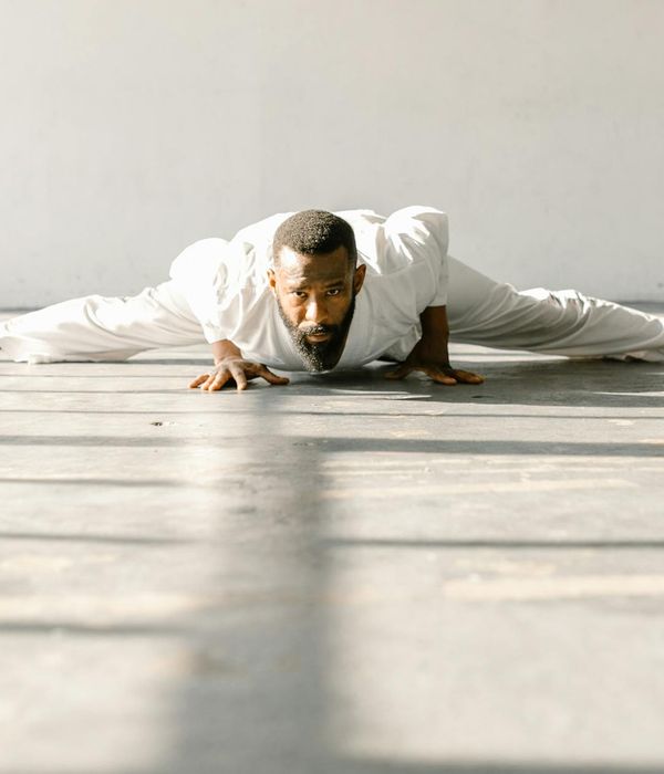 Man performing a controlled strength exercise in a minimalist dark room.
